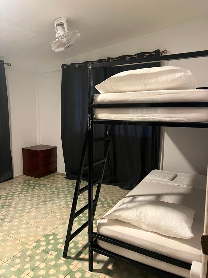 Litera con ropa de cama blanca junto a la ventana.
