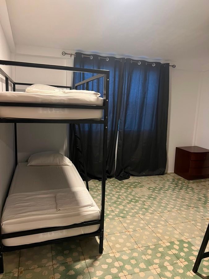 Habitación con litera, mesa de noche y cortinas.